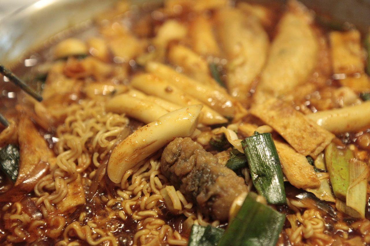 Delicious spread of Tteokbokki, ramen, and assorted vegetables at Hwa Tteok, Seoul, offering a spicy culinary adventure.